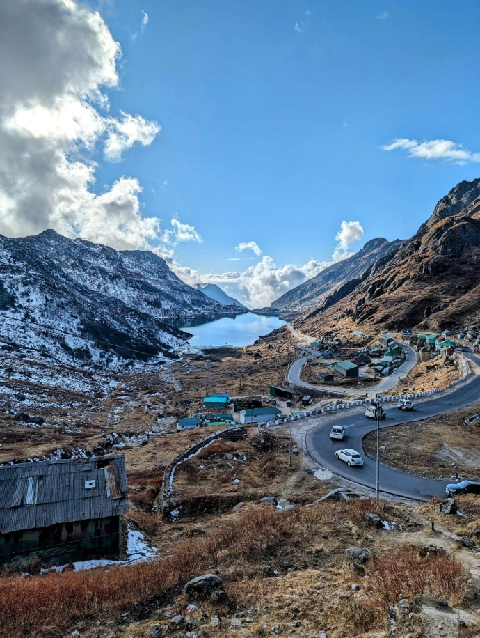 a scenic view of a mountain road with a lake in the distance