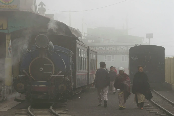 People walk near a foggy train station.